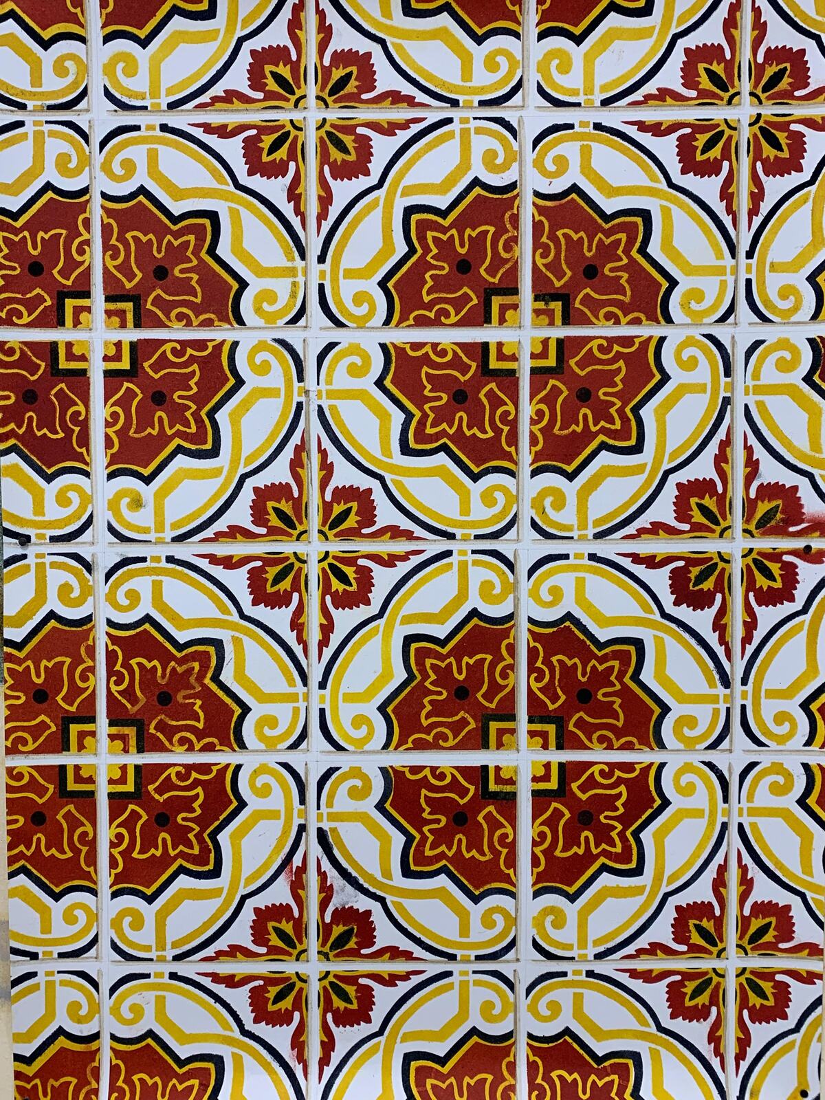 Décor de carreaux de faïence peints, motif floral rouge et jaune.